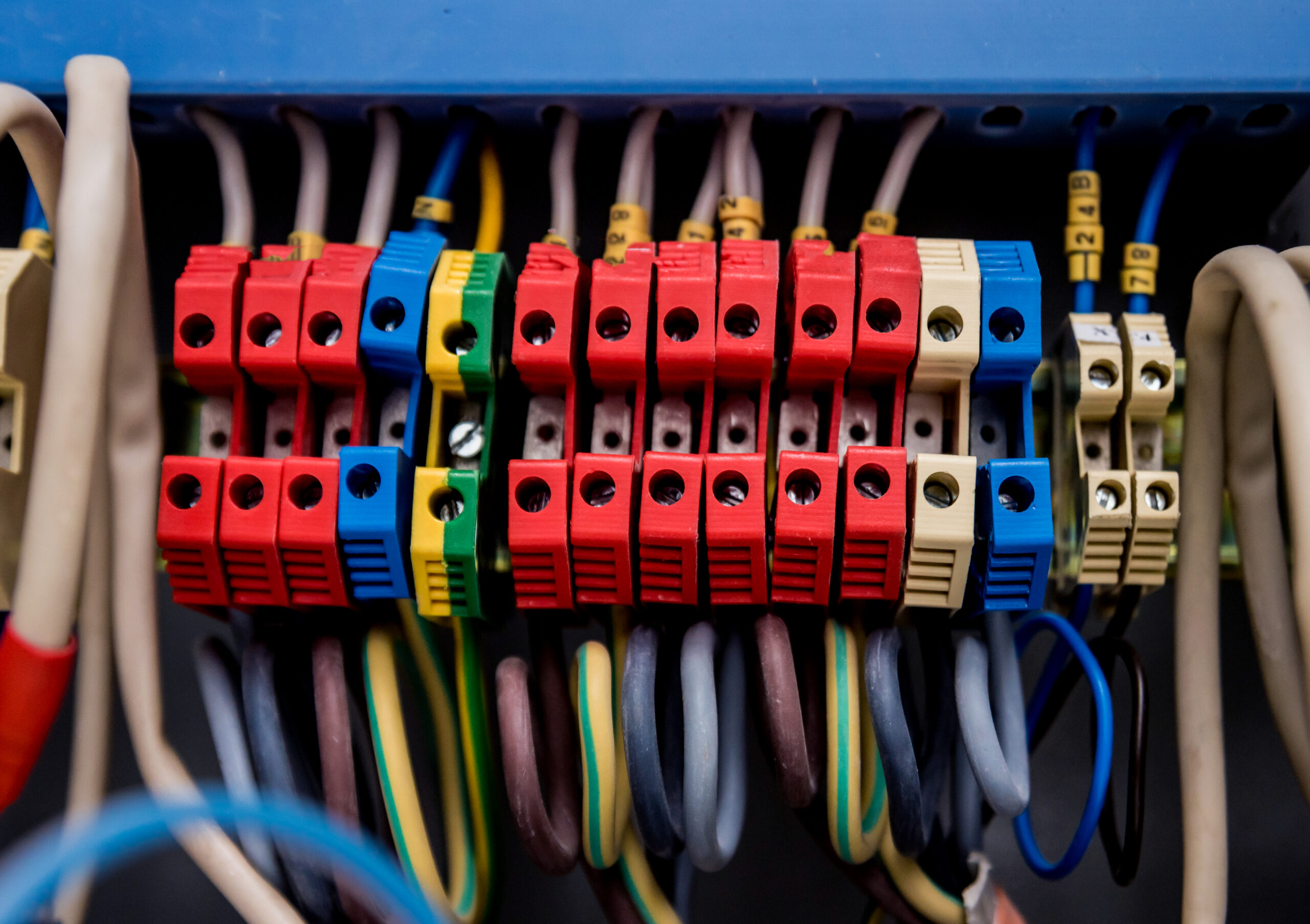 Close-up of colorful modular terminal blocks and cables in a network patch panel, showing red, blue, yellow, green blocks and tagged wires.